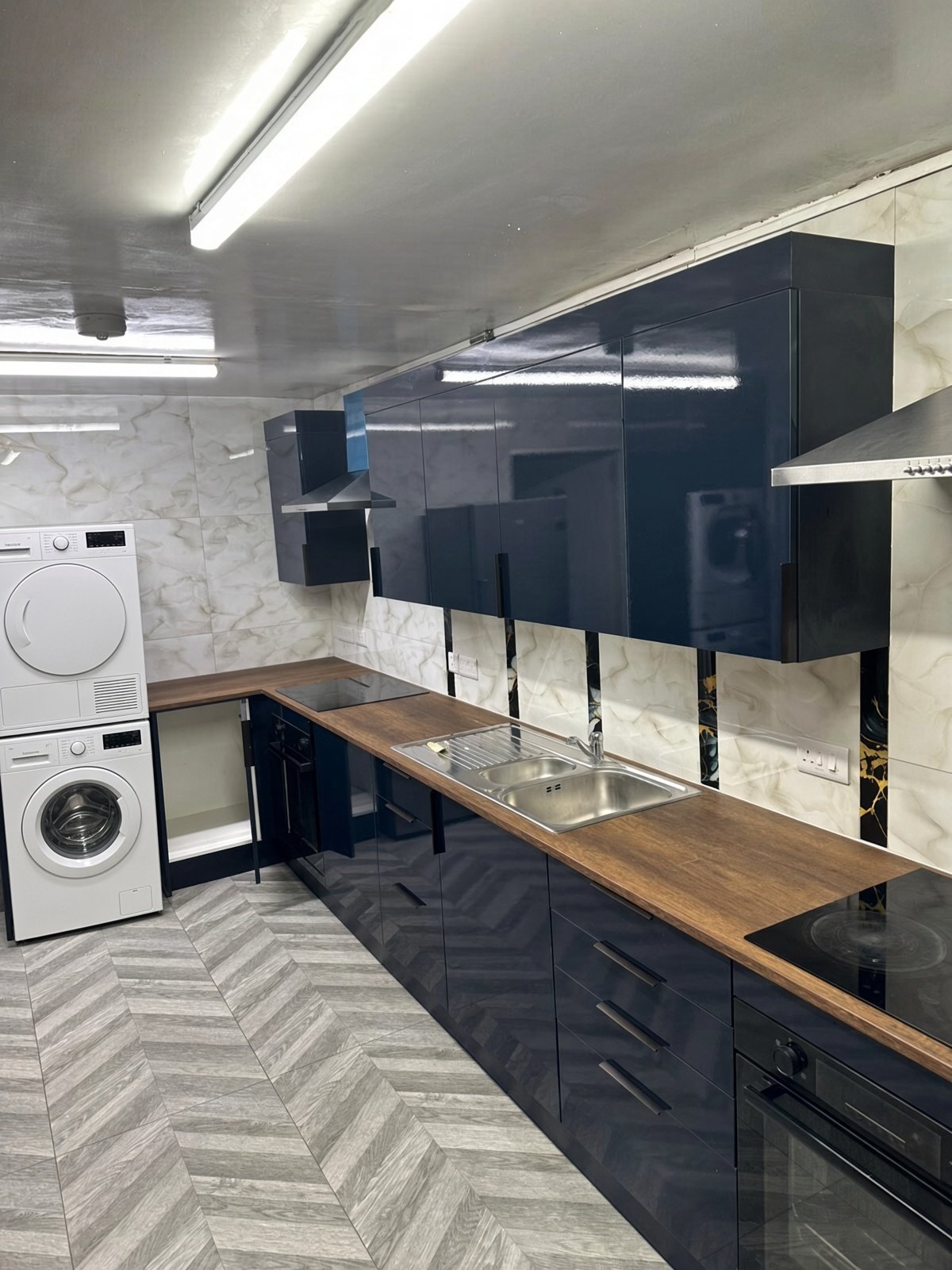 Kitchen with navy units, wood worktops and stacked washer and dryer