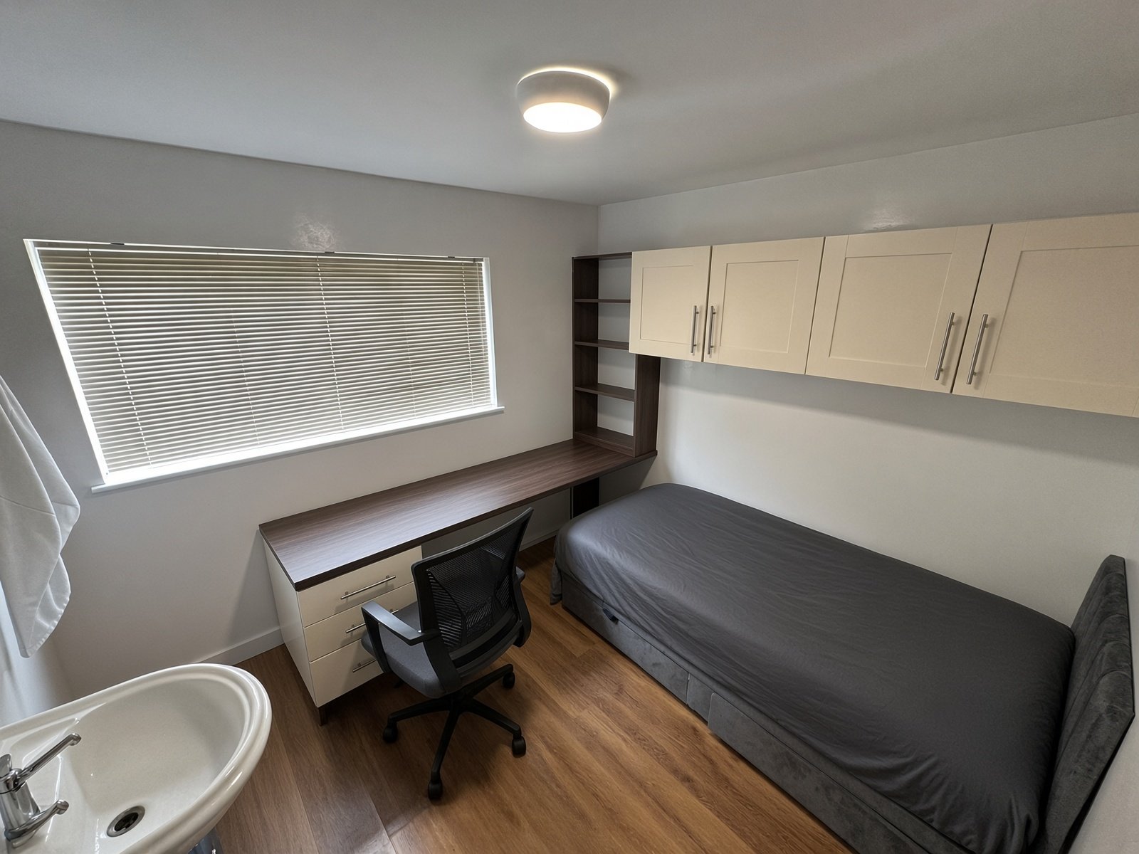 Bedroom with desk, wall cupboards and washbasin