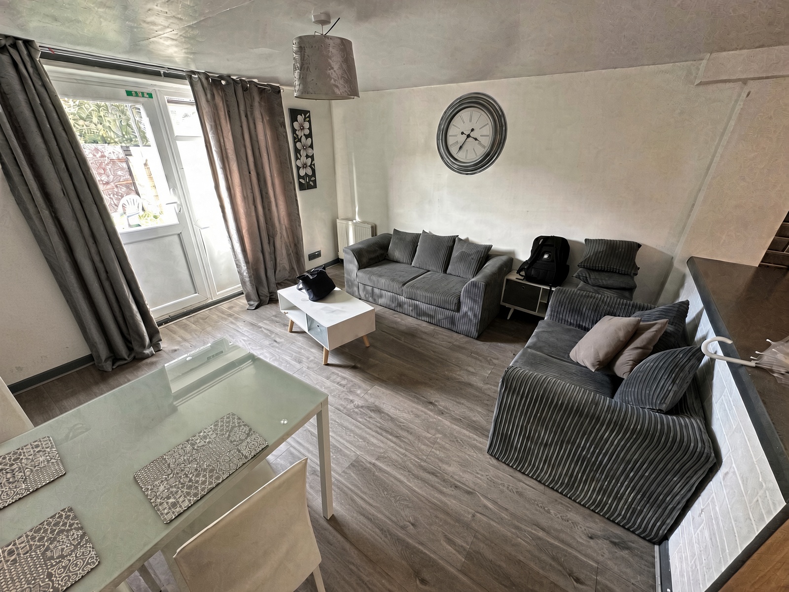 Living and dining room with grey sofas, white coffee table, and glass patio doors