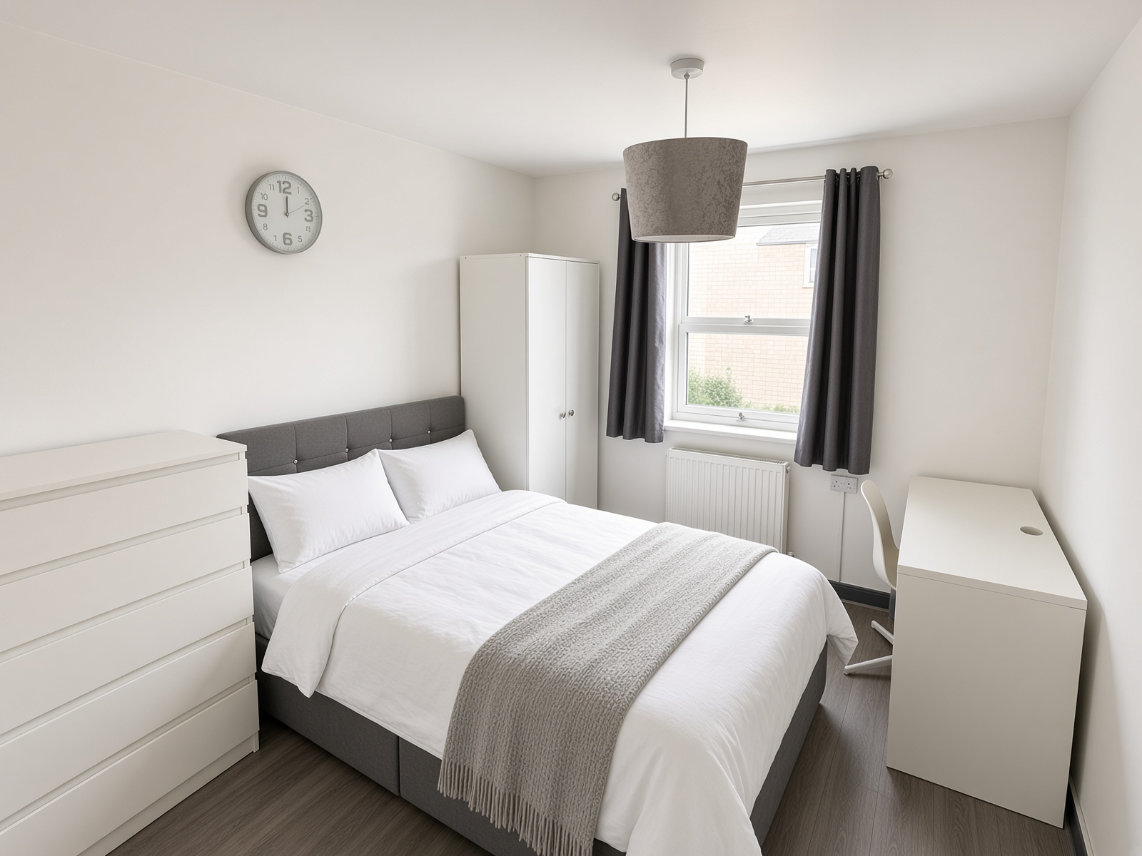Bedroom with grey headboard, white wardrobe, desk and drawers under the window
