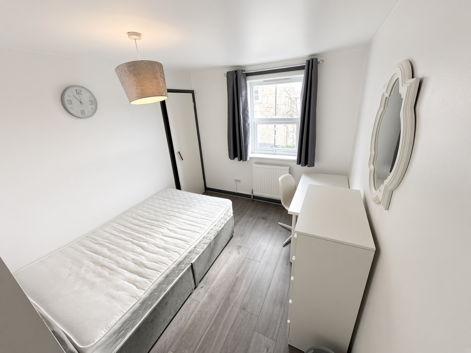Bedroom with single bed, white drawers, desk and chair under the window