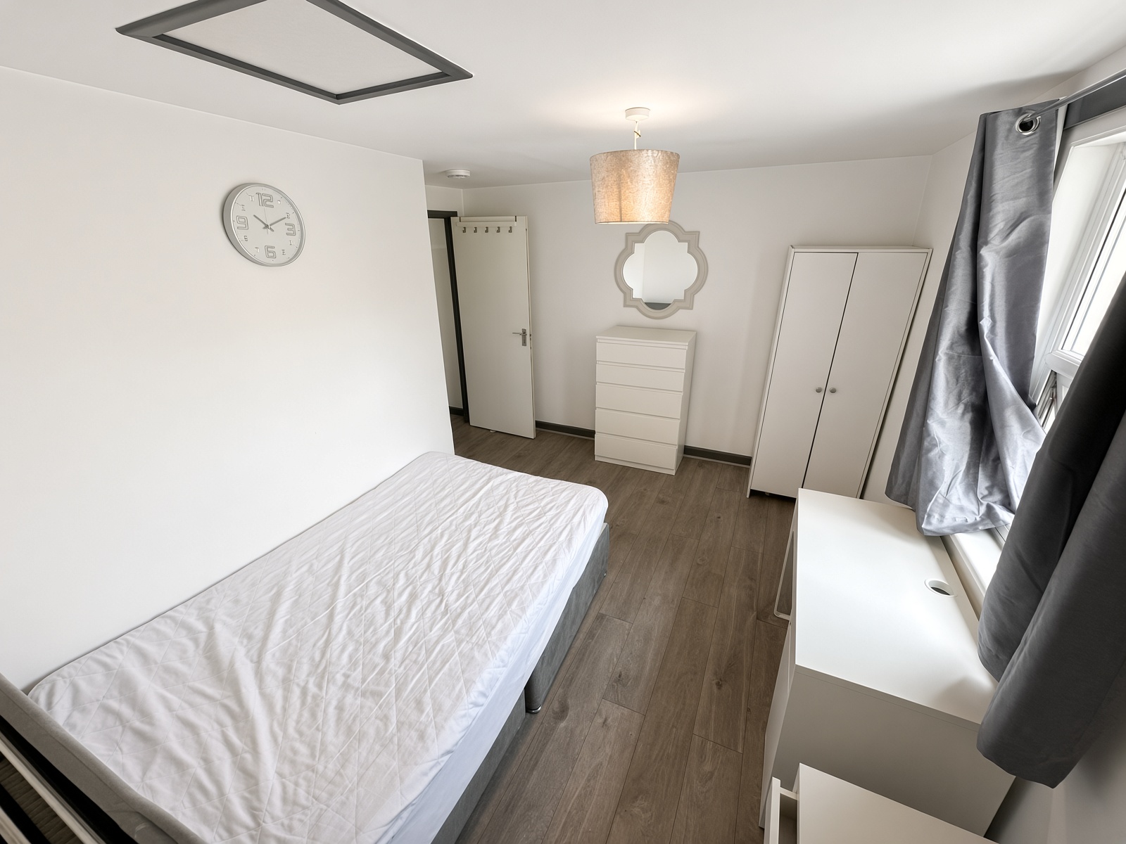 Bedroom with single bed, white wardrobe, drawers and desk