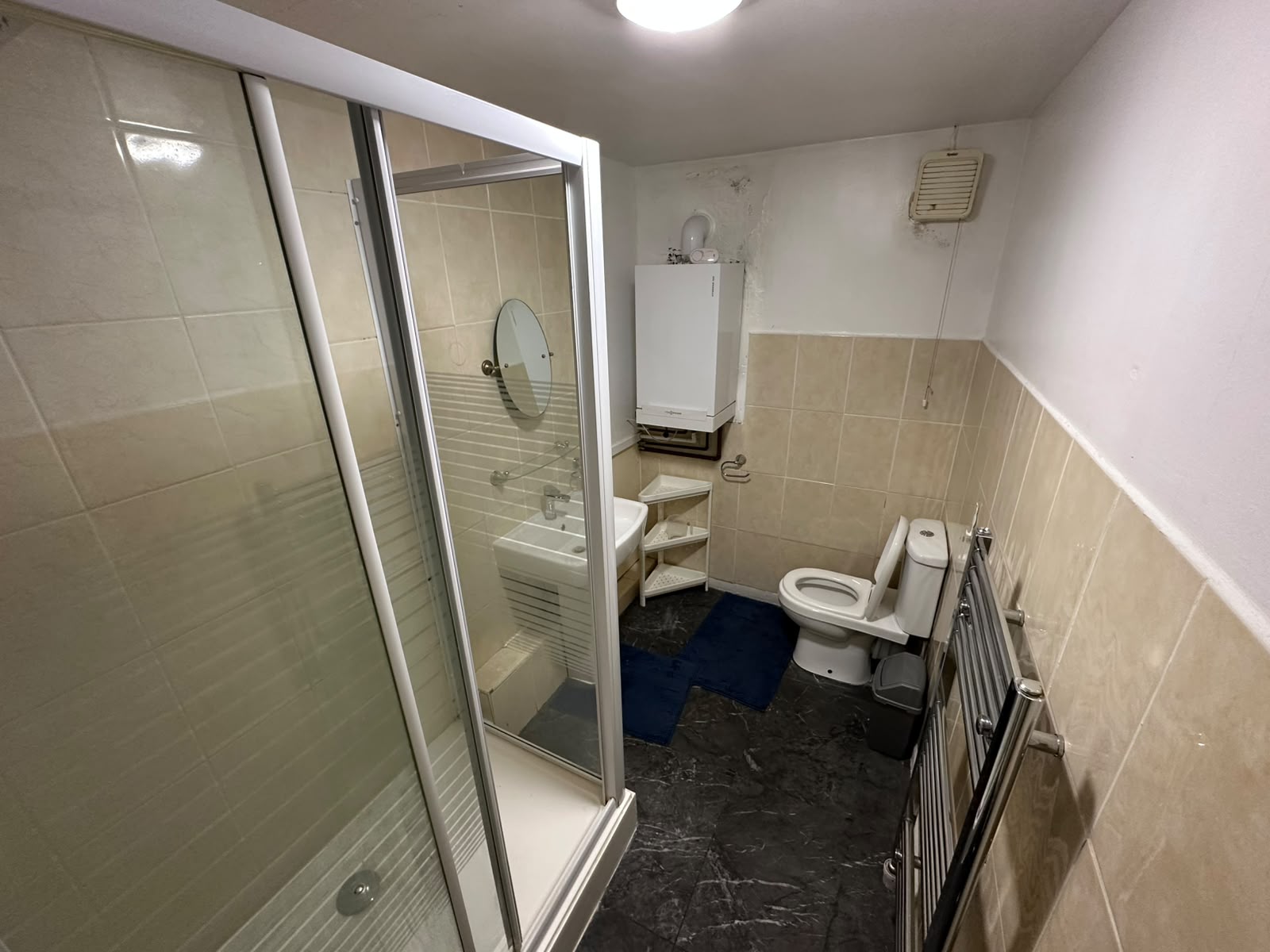 Bathroom with corner shower cubicle, pedestal sink, toilet and heated towel rail