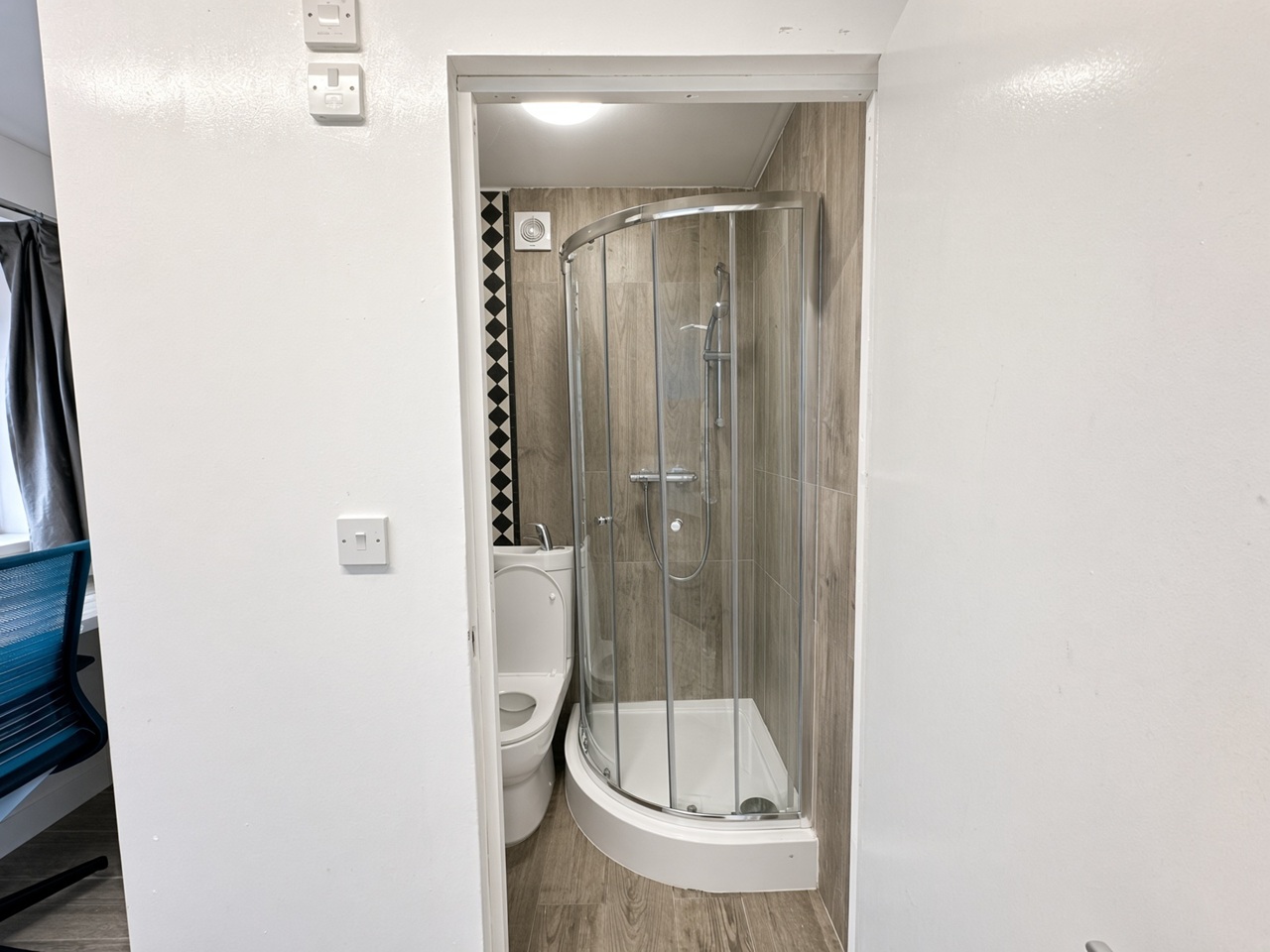 Ensuite shower room seen through the doorway, with a glass cubicle and a basin on the cistern