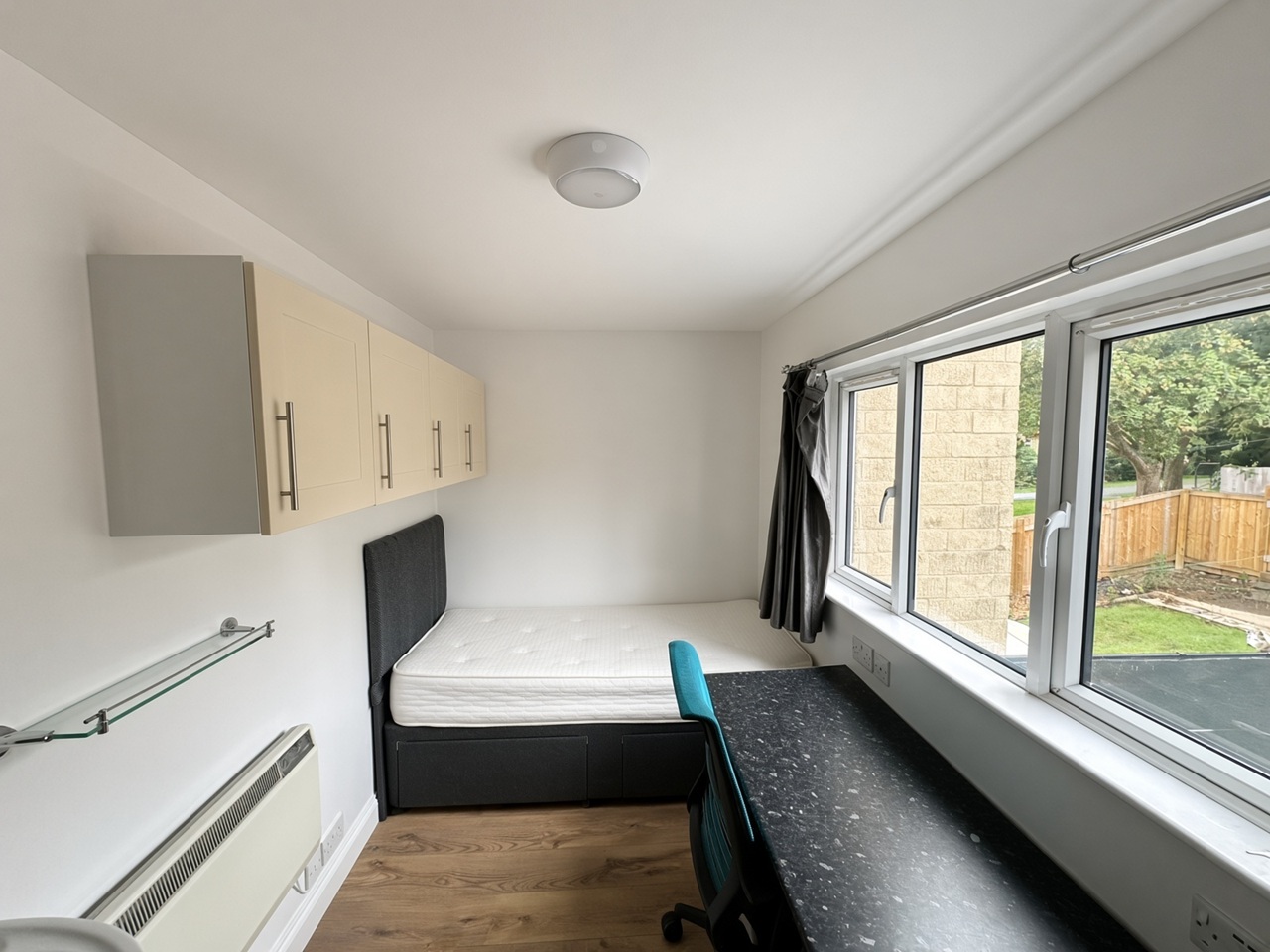Bedroom with a black desk, teal chair, and a wall sink