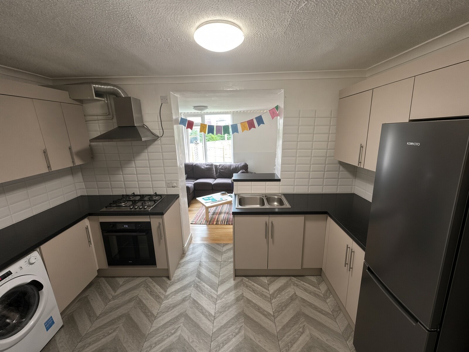 Kitchen with grey units, black worktops and fridge freezer