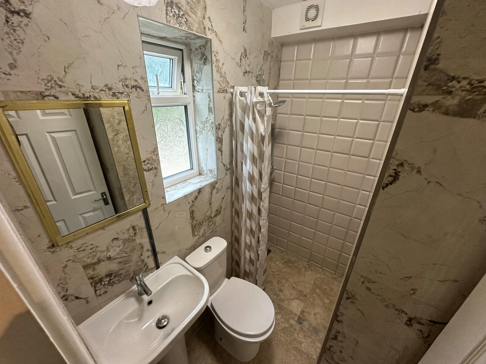 Shower room with marble-effect walls, basin and WC