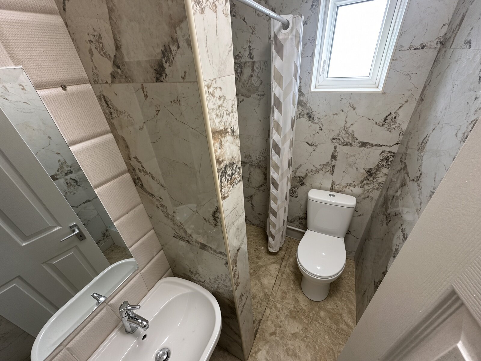 Shower room with marble-effect tiles, WC and basin