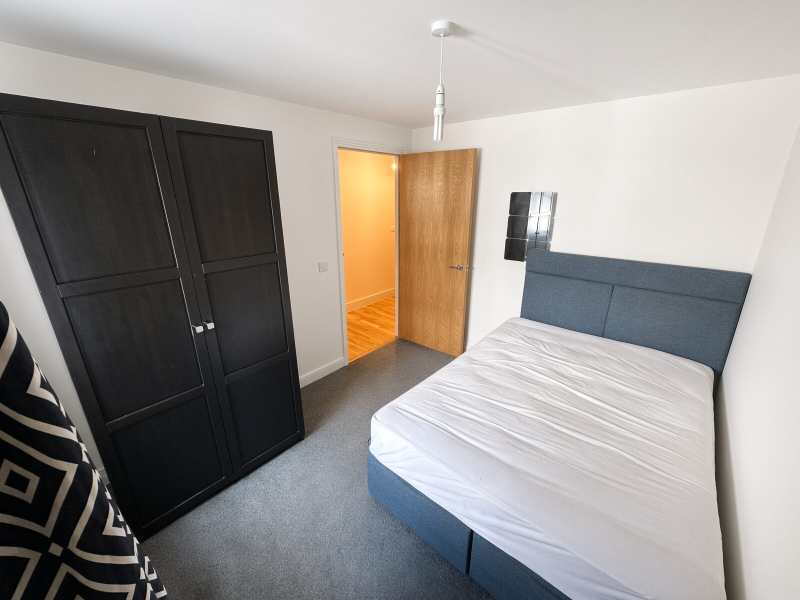 Bedroom with blue-grey headboard and dark wardrobe