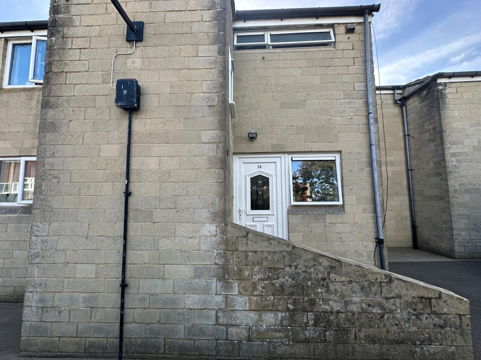 Side of the house with stone walls and white entrance door