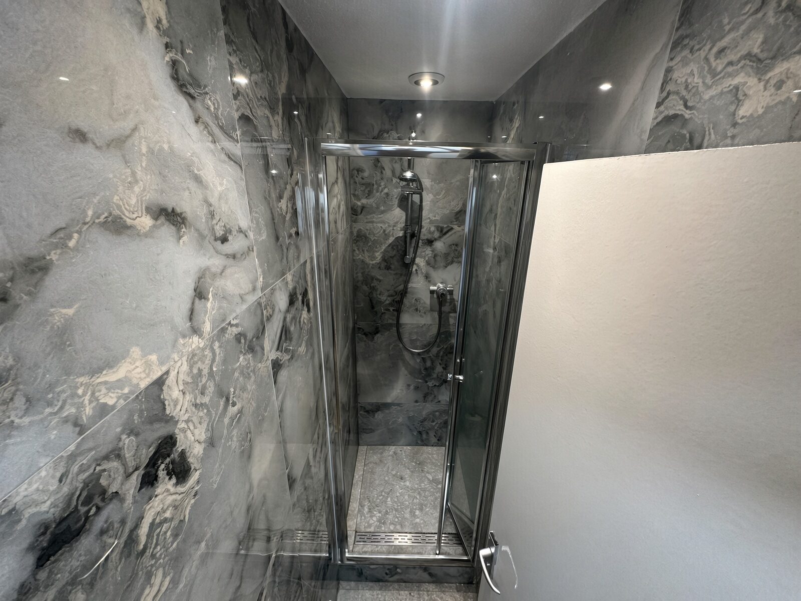 Shower room with marble-effect walls and glass shower