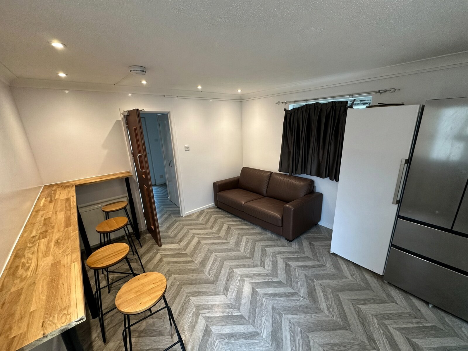 Living room with sofa, breakfast bar and fridge freezer