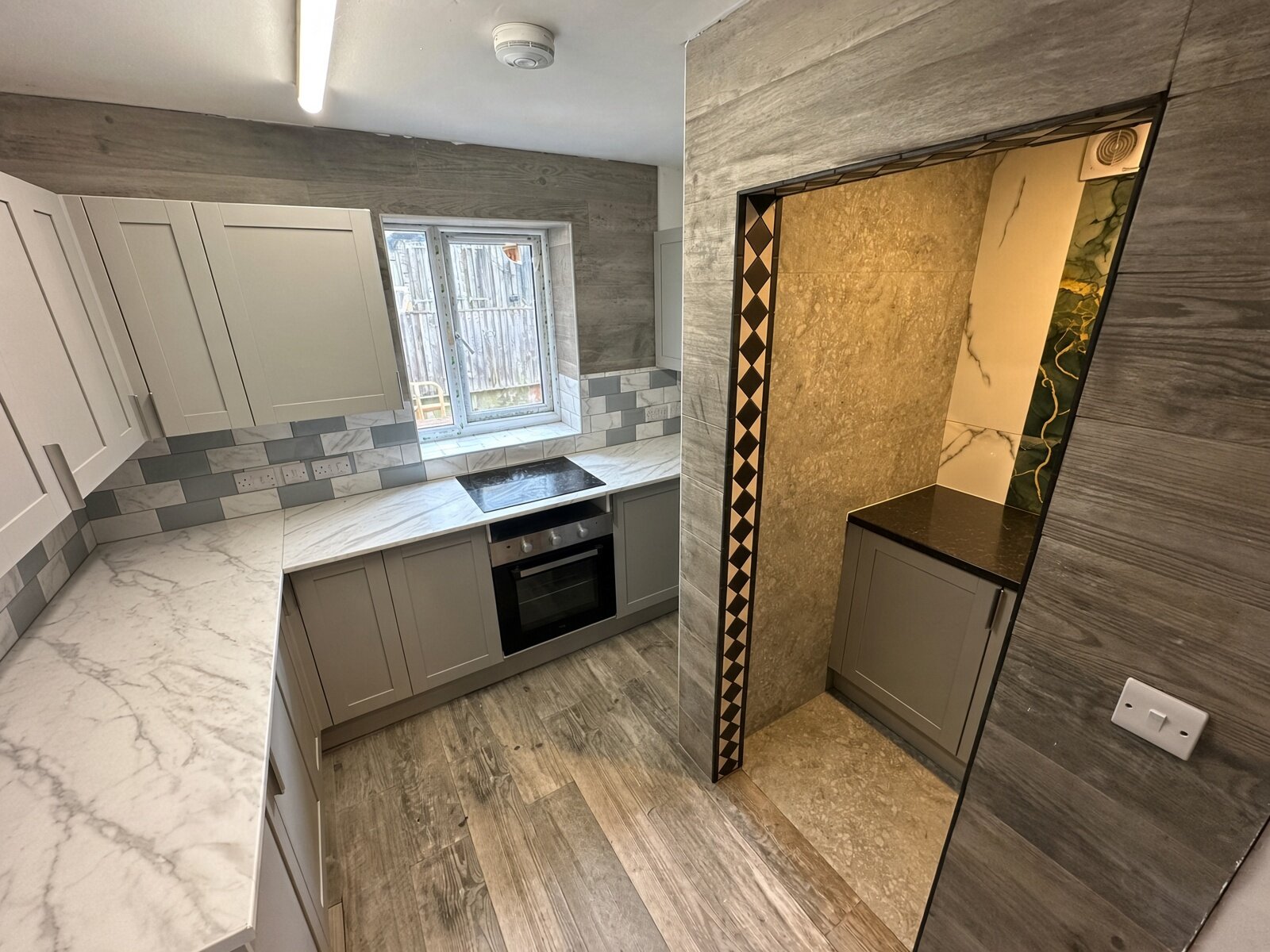 Kitchen with grey units, marble-effect worktops and oven