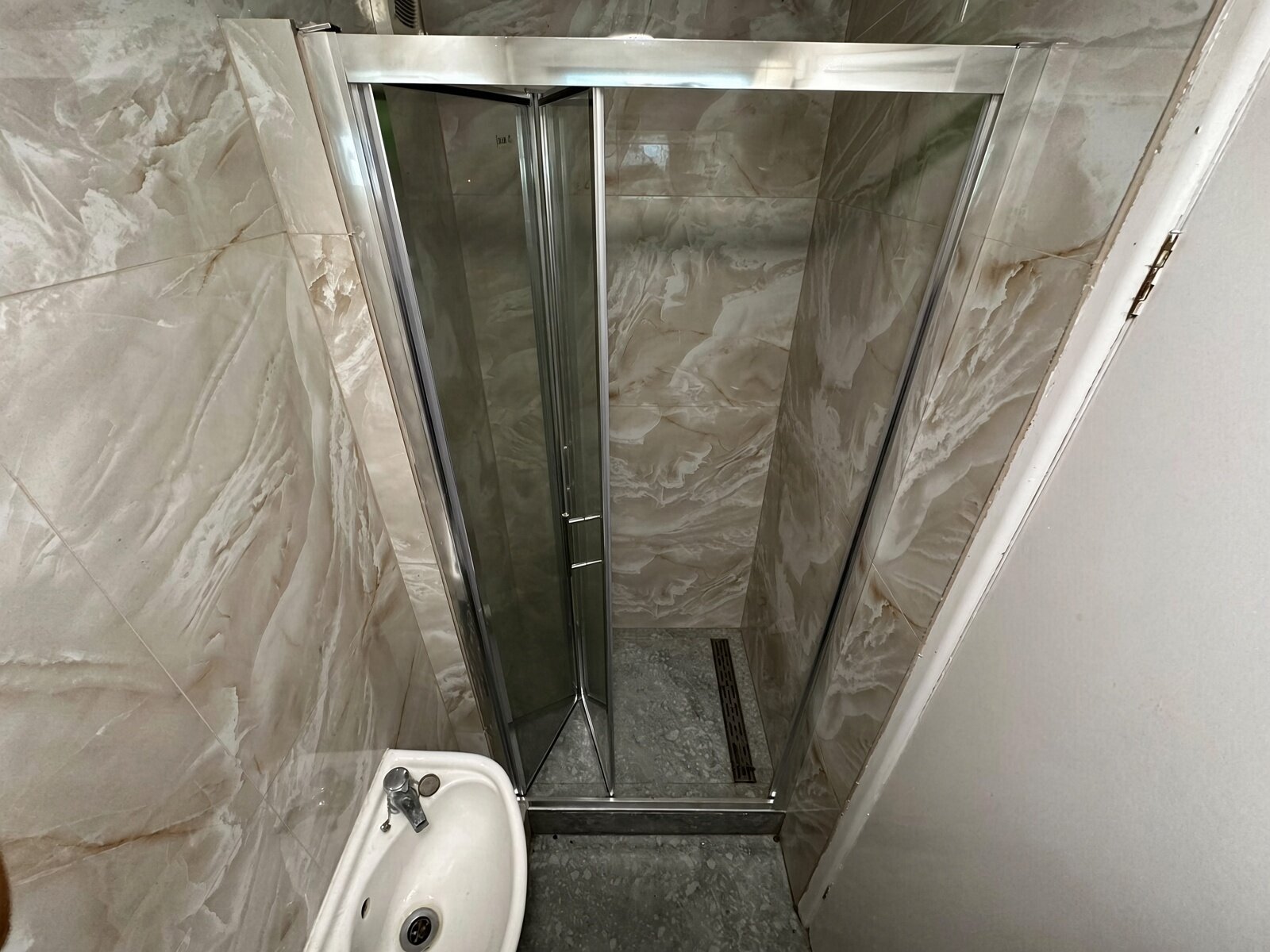 Shower room with glass shower enclosure and marble-effect walls
