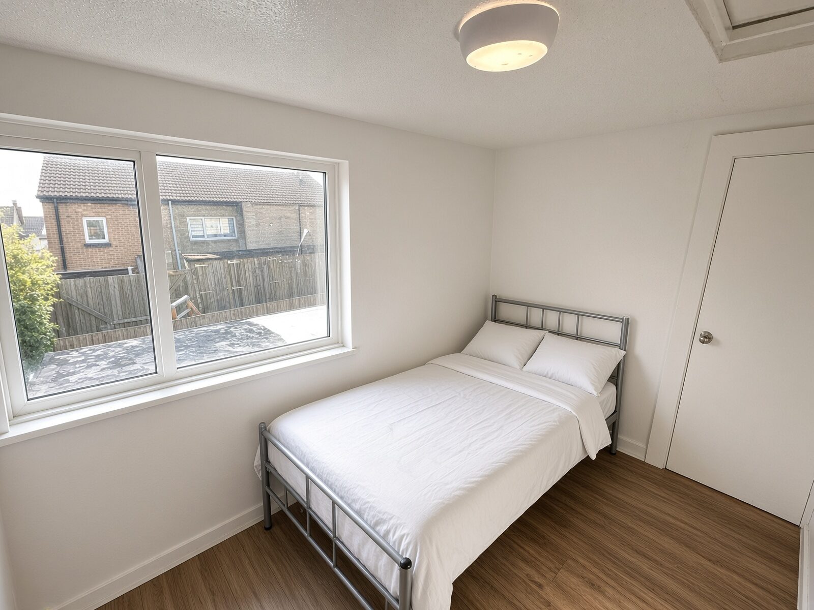 Bedroom with double bed, white bedding and window overlooking the street