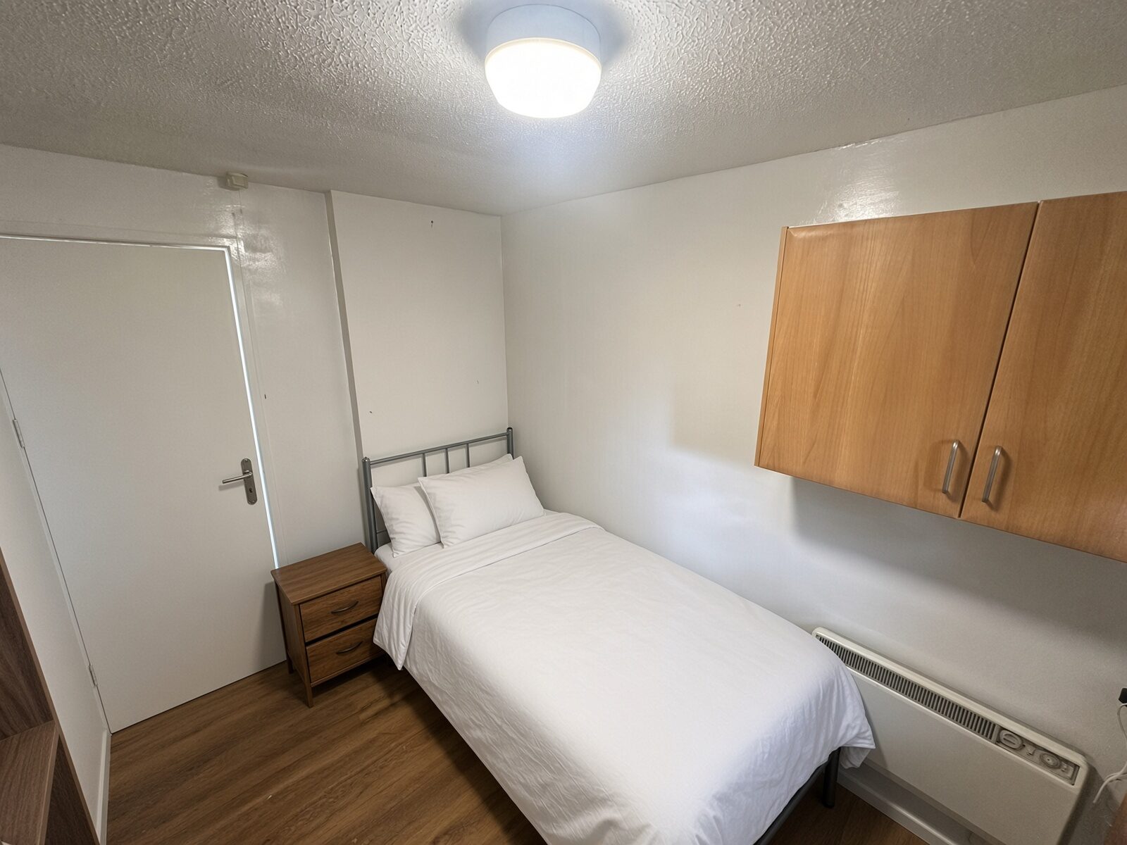 Bedroom with single bed, bedside table and wall cupboards