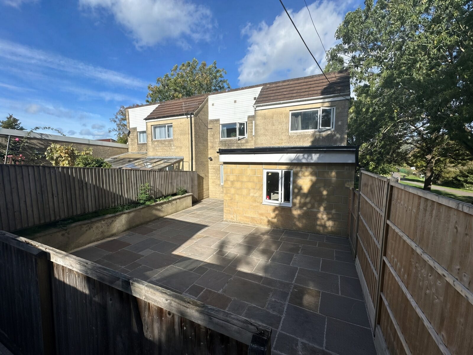 Paved rear garden with raised bed and timber fencing