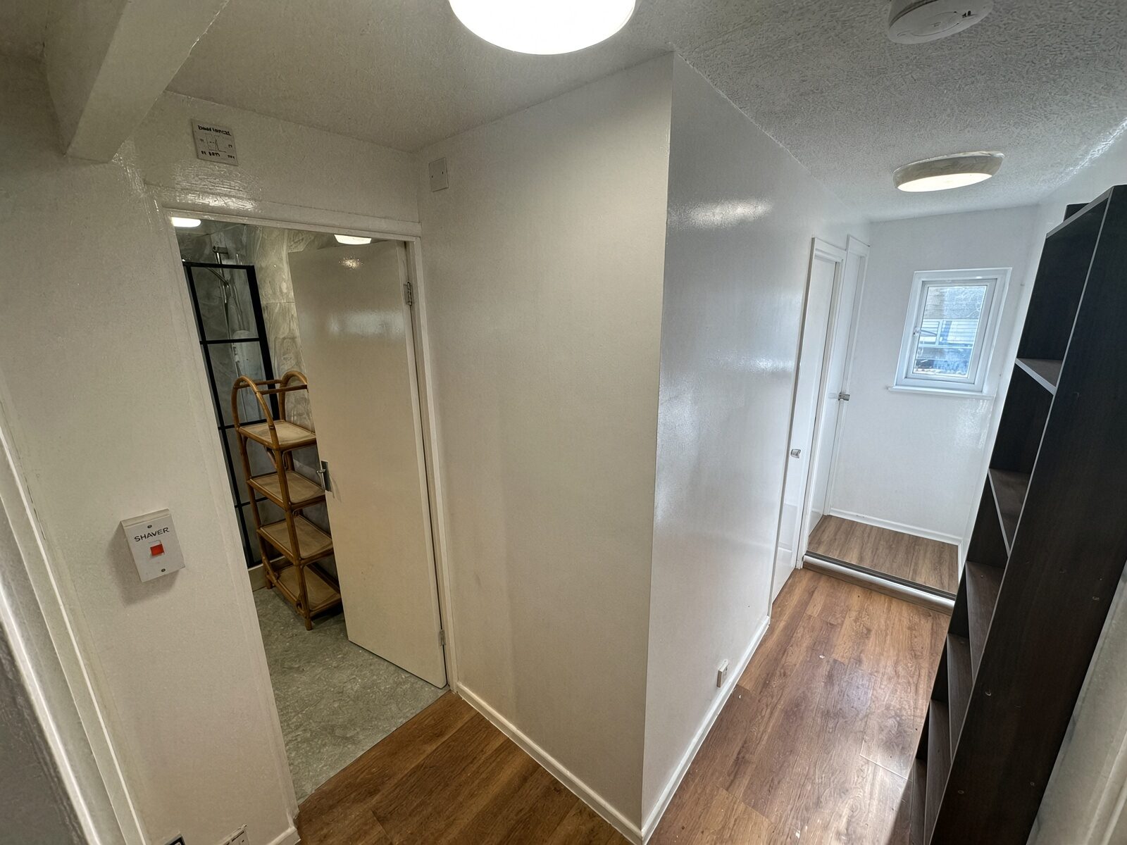 Hallway with wood floor leading to the shower room