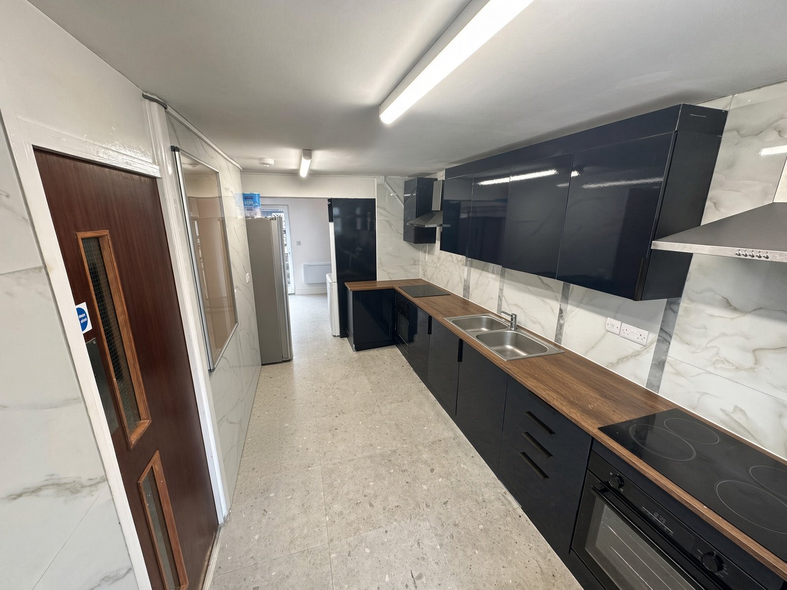 Galley kitchen with navy units and wood worktops