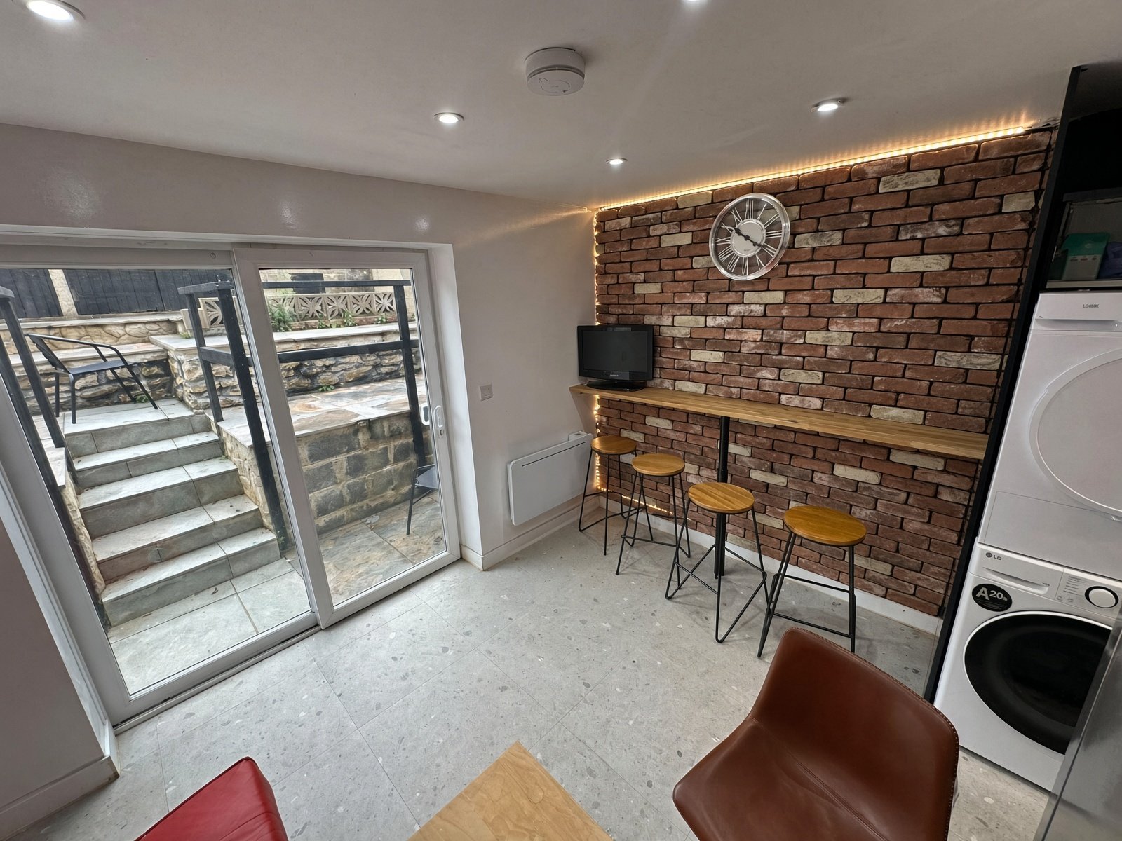 Kitchen dining area with brick feature wall, breakfast bar and garden doors