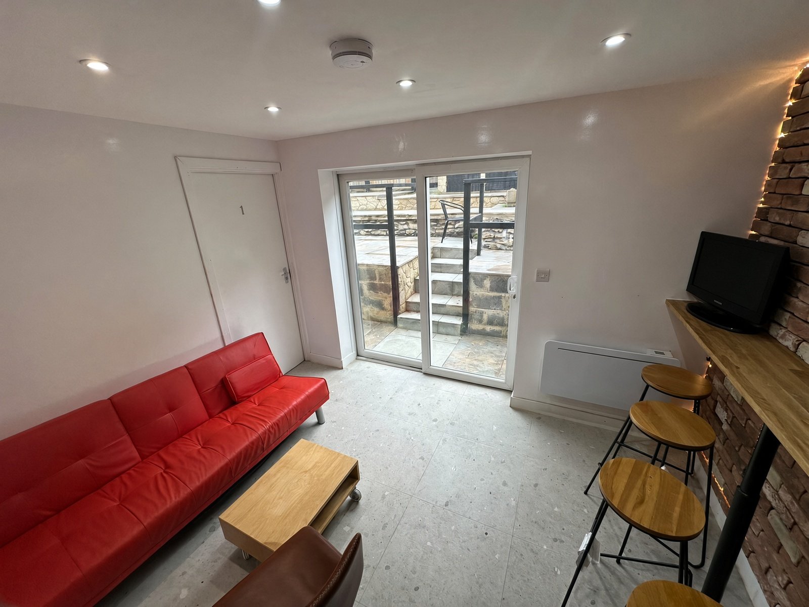 Living room with red sofa, breakfast bar and patio doors
