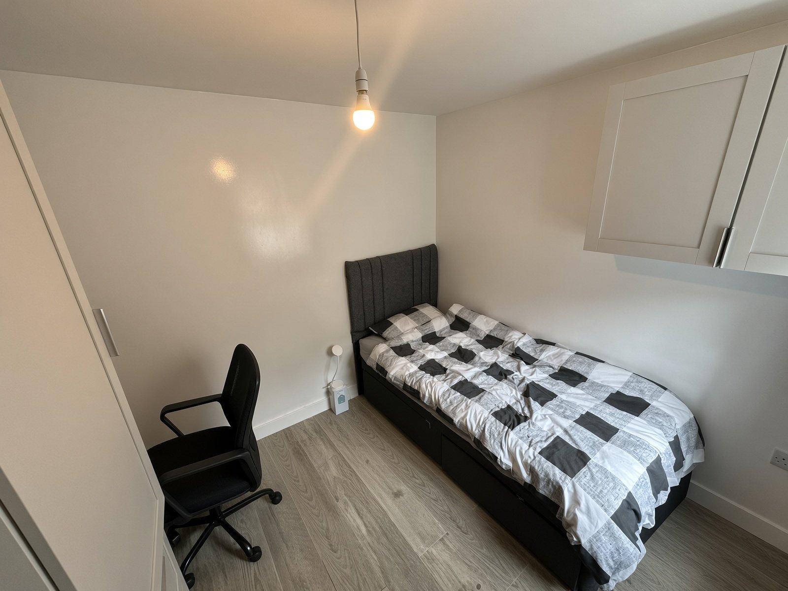 Bedroom with checked bedding, desk chair and pendant light