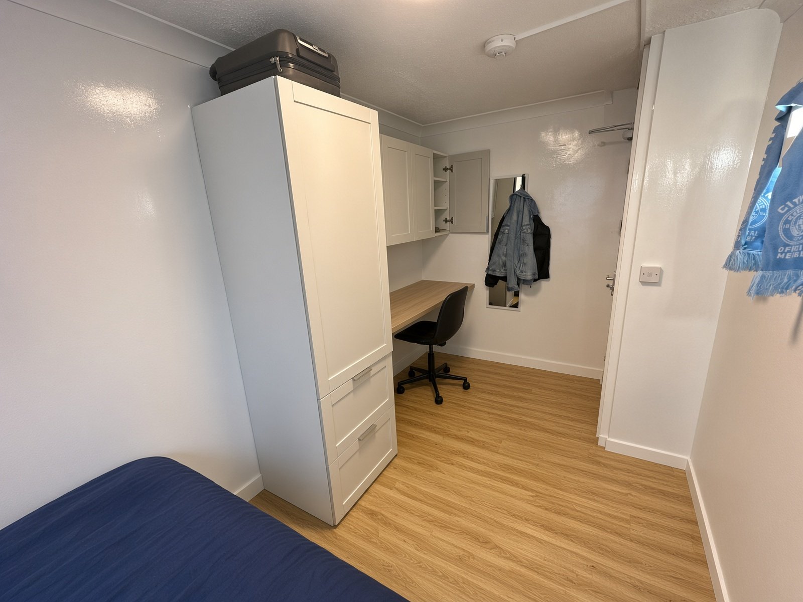 Bedroom with tall wardrobe, desk and wood floor
