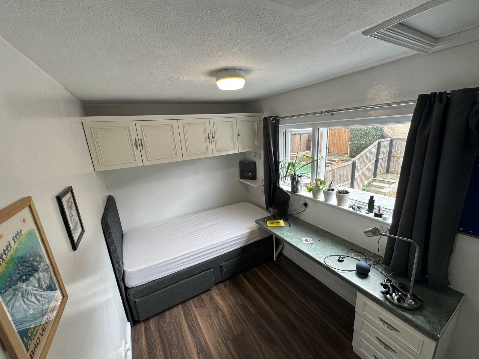Bedroom with bed, window desk and overhead cupboards