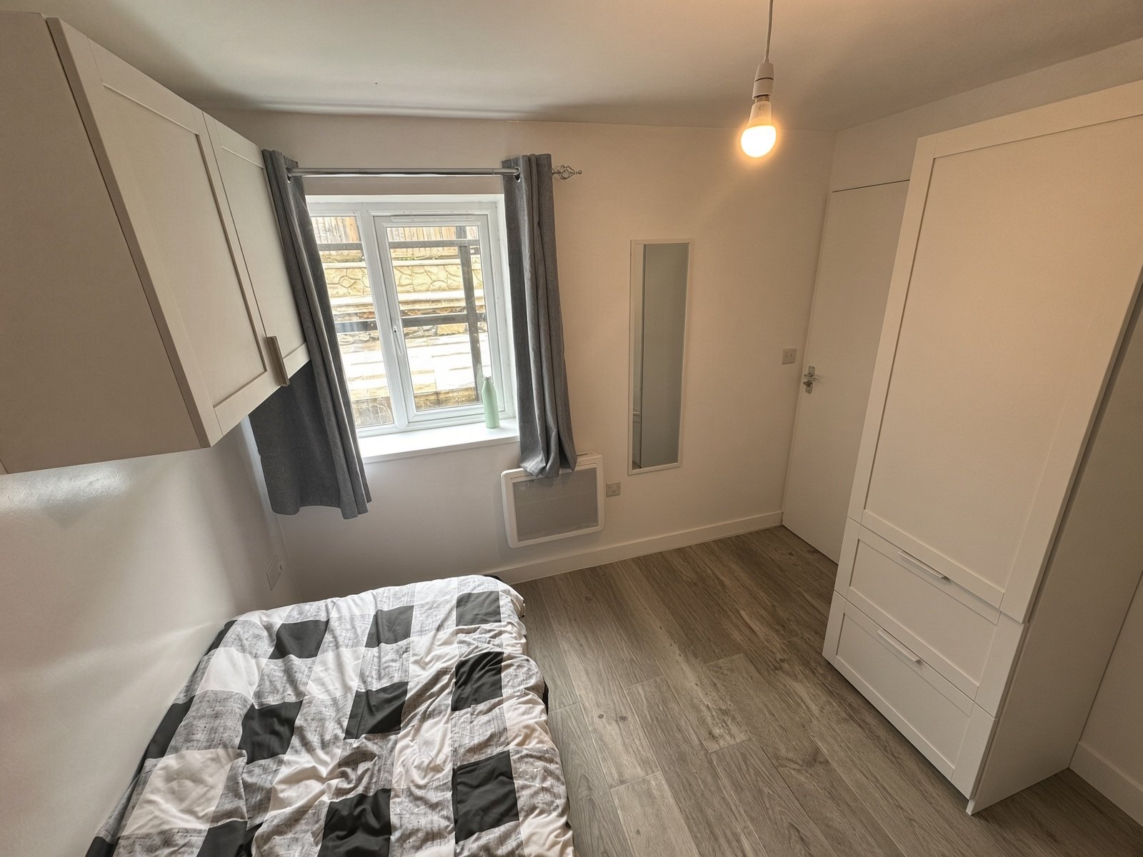 Bedroom with checked bedding, wardrobe and radiator