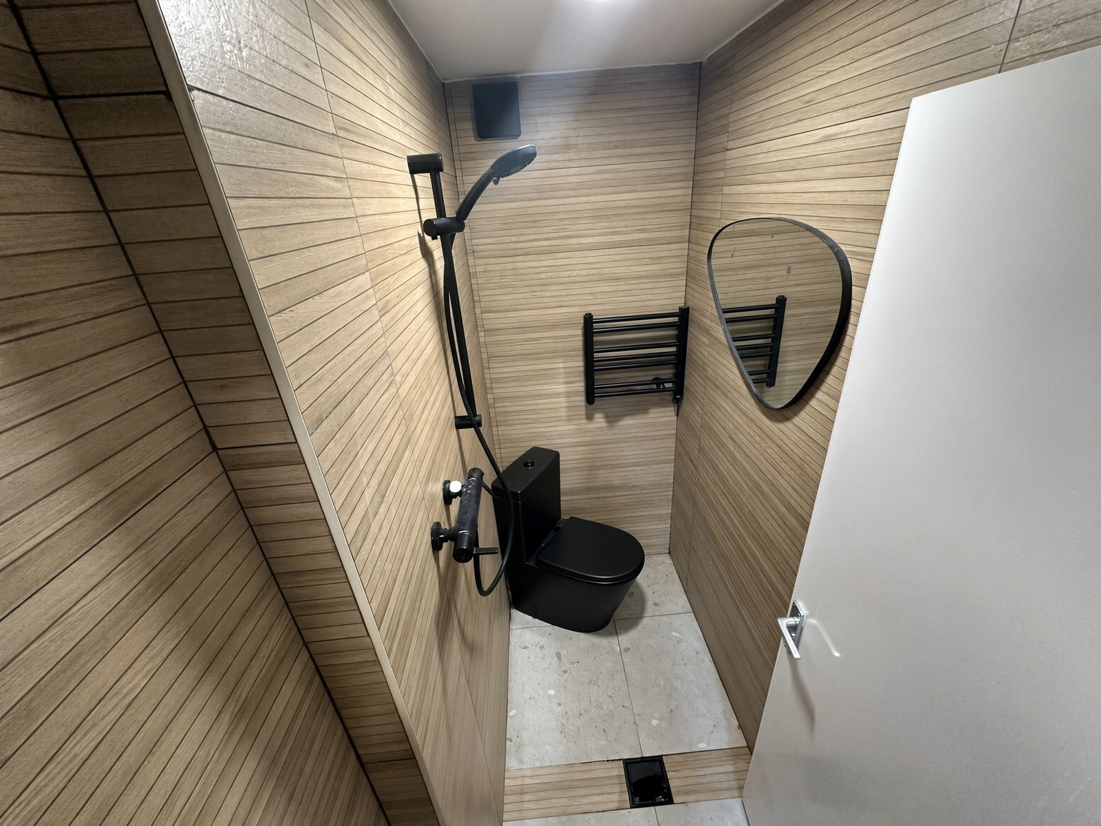 Shower room with wood-effect walls, black fittings and round mirror