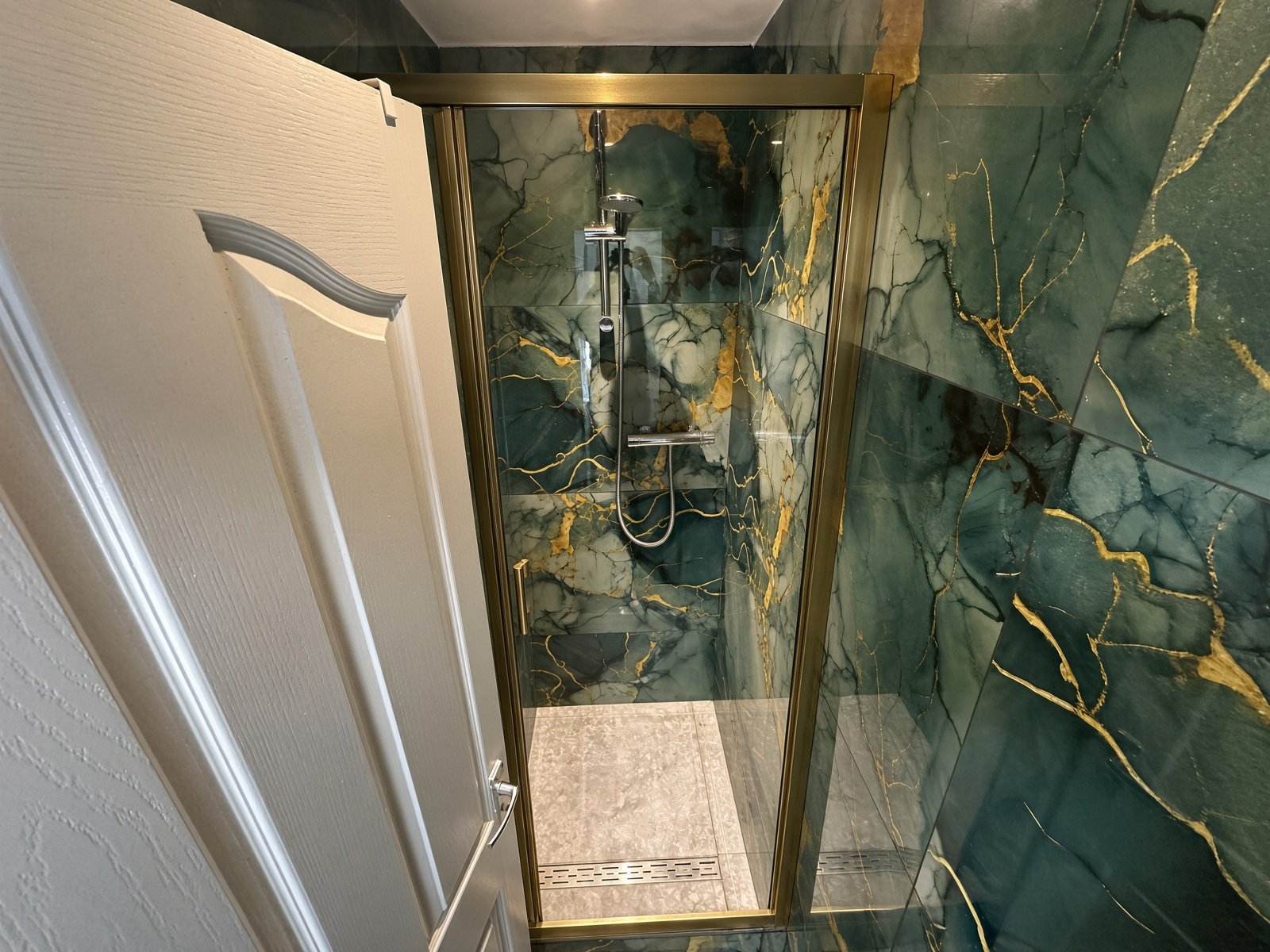 Shower with green and gold marble-effect walls