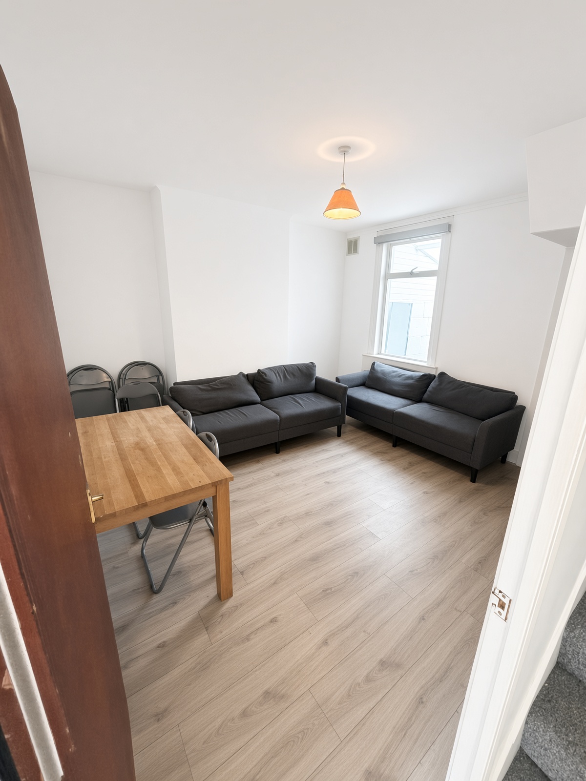 Communal living and dining room with grey sofas and a dining table