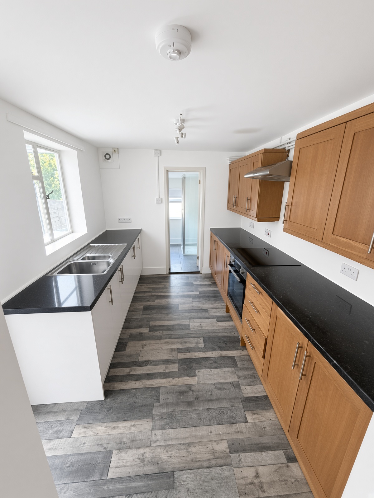Galley kitchen with white and oak cabinets and a black worktop