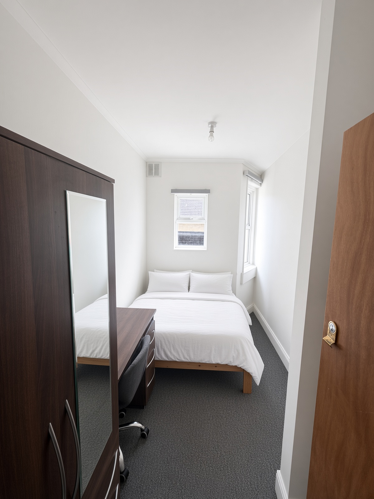 Narrow bedroom with a high window above the bed