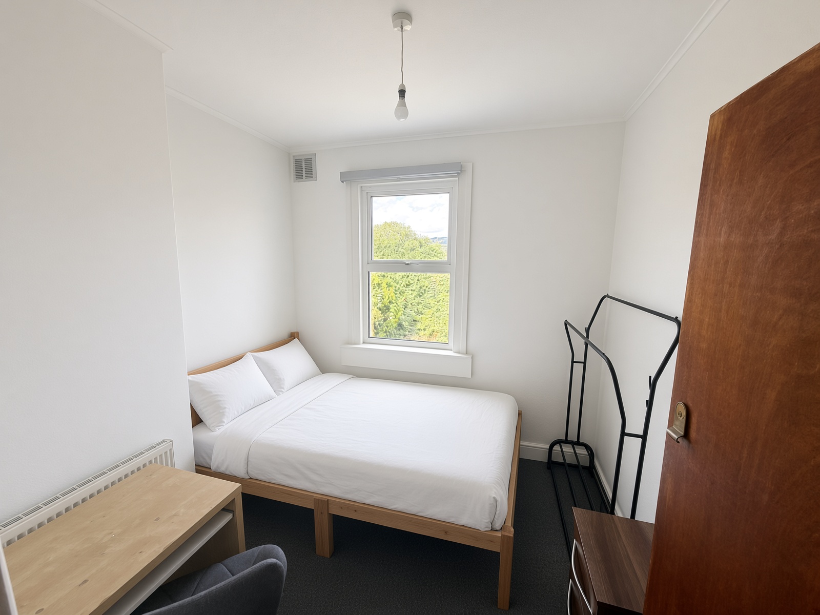 Bedroom with a wooden bed, desk, and black clothes rail