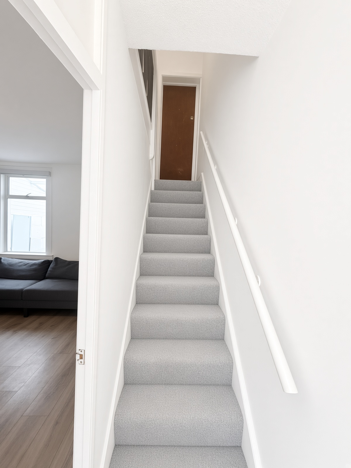 Hallway staircase looking up, with grey carpet and a white handrail