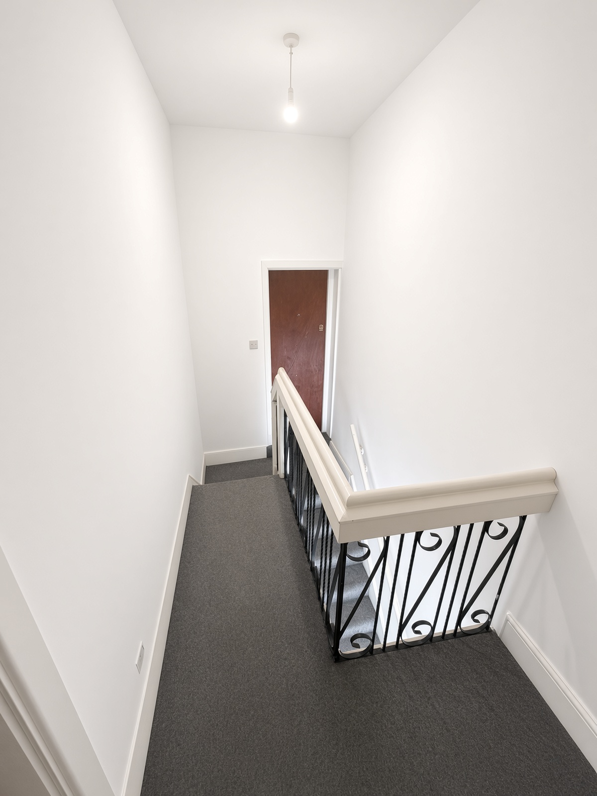 Upper landing with dark grey carpet and a wrought-iron banister