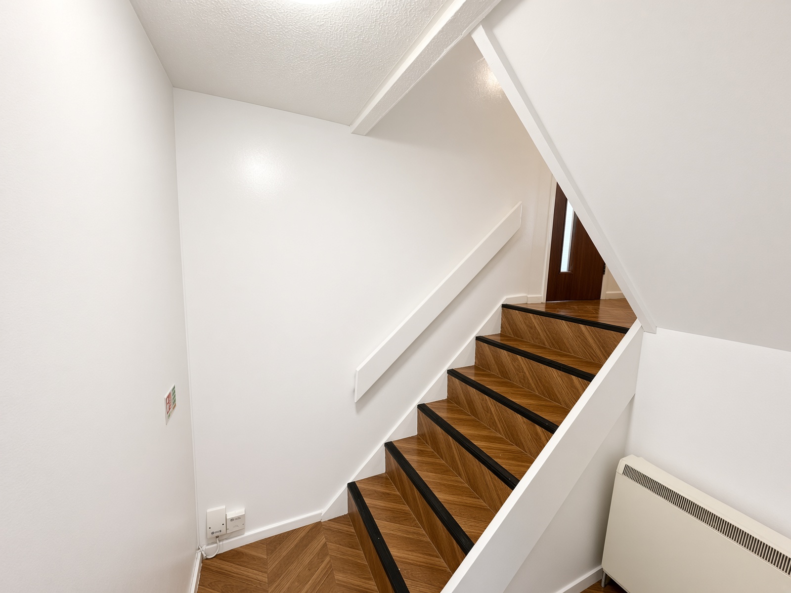 Stairs with herringbone wood-effect treads and black anti-slip strips