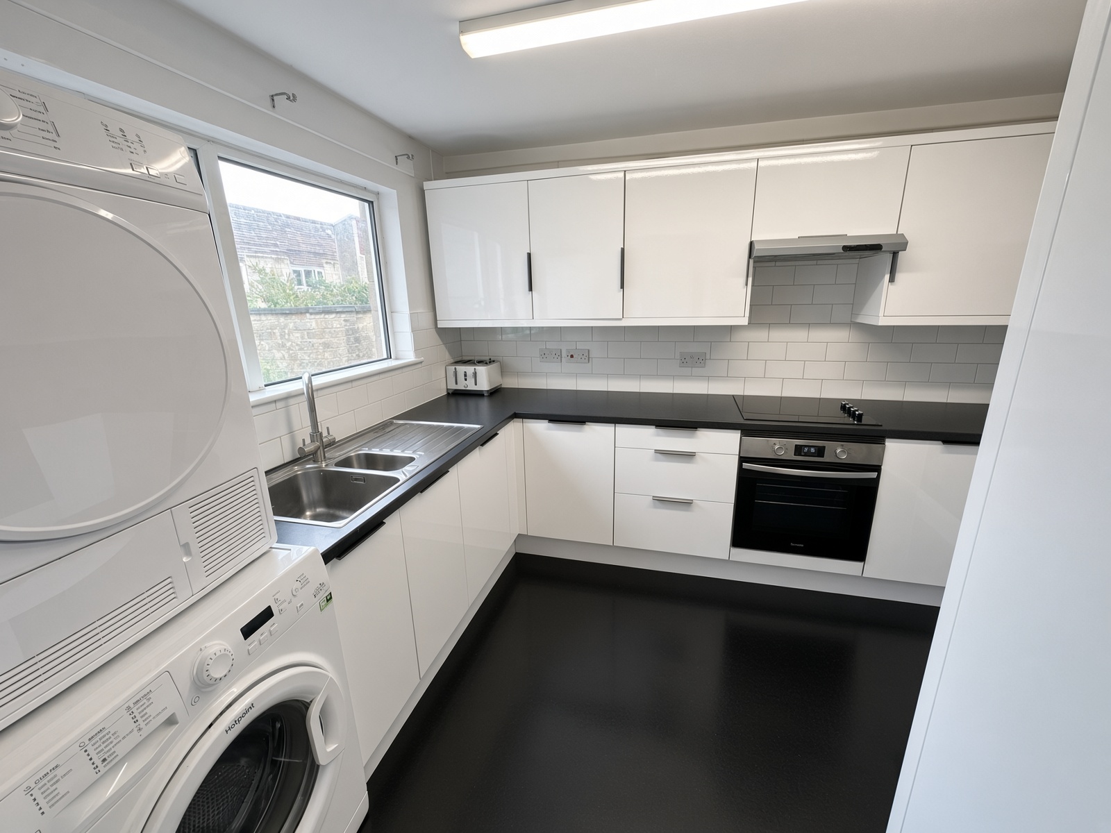 L-shaped kitchen with a washer-dryer stack and a sink under the window