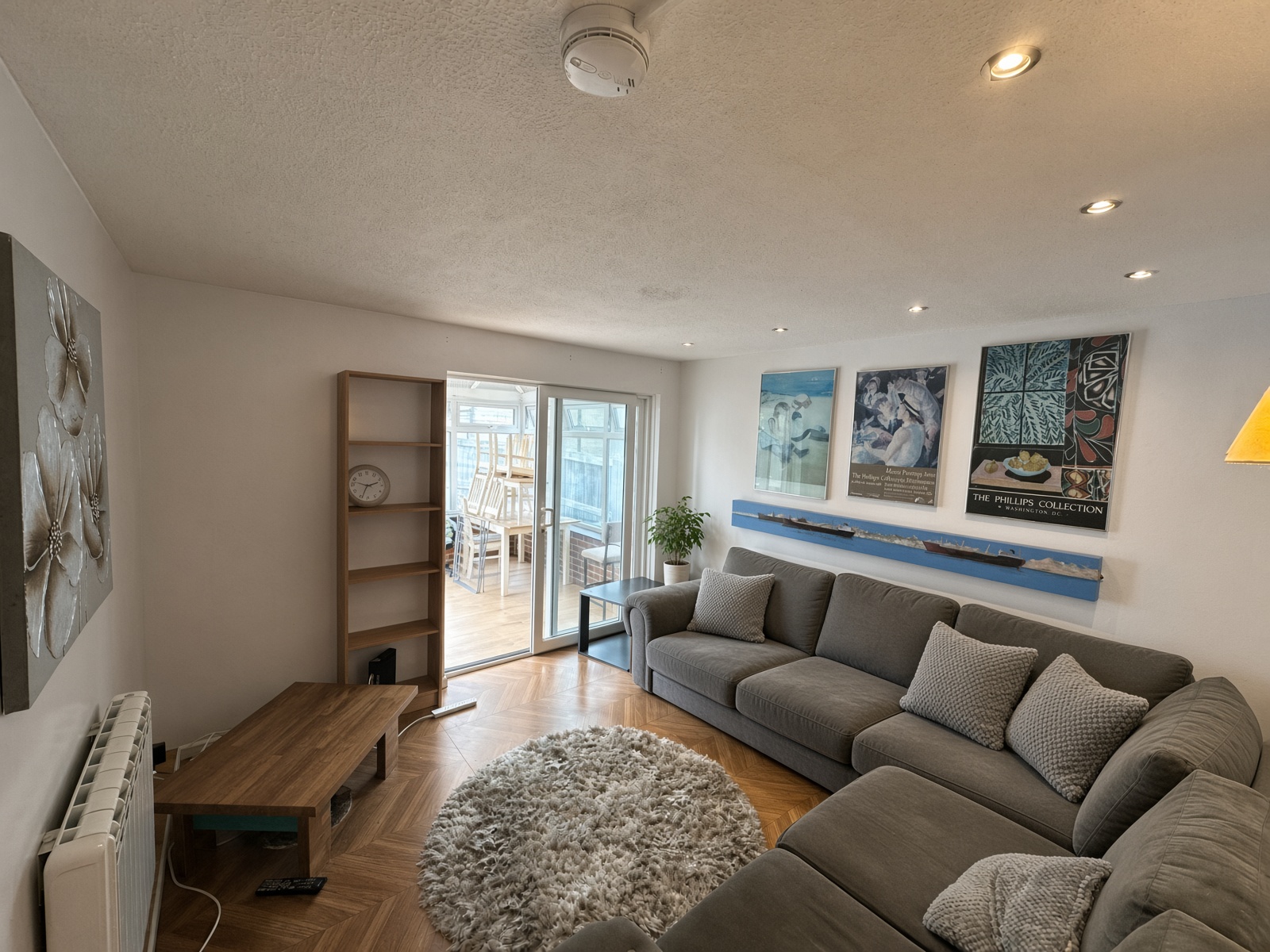 Living room with a grey corner sofa and sliding doors to the conservatory
