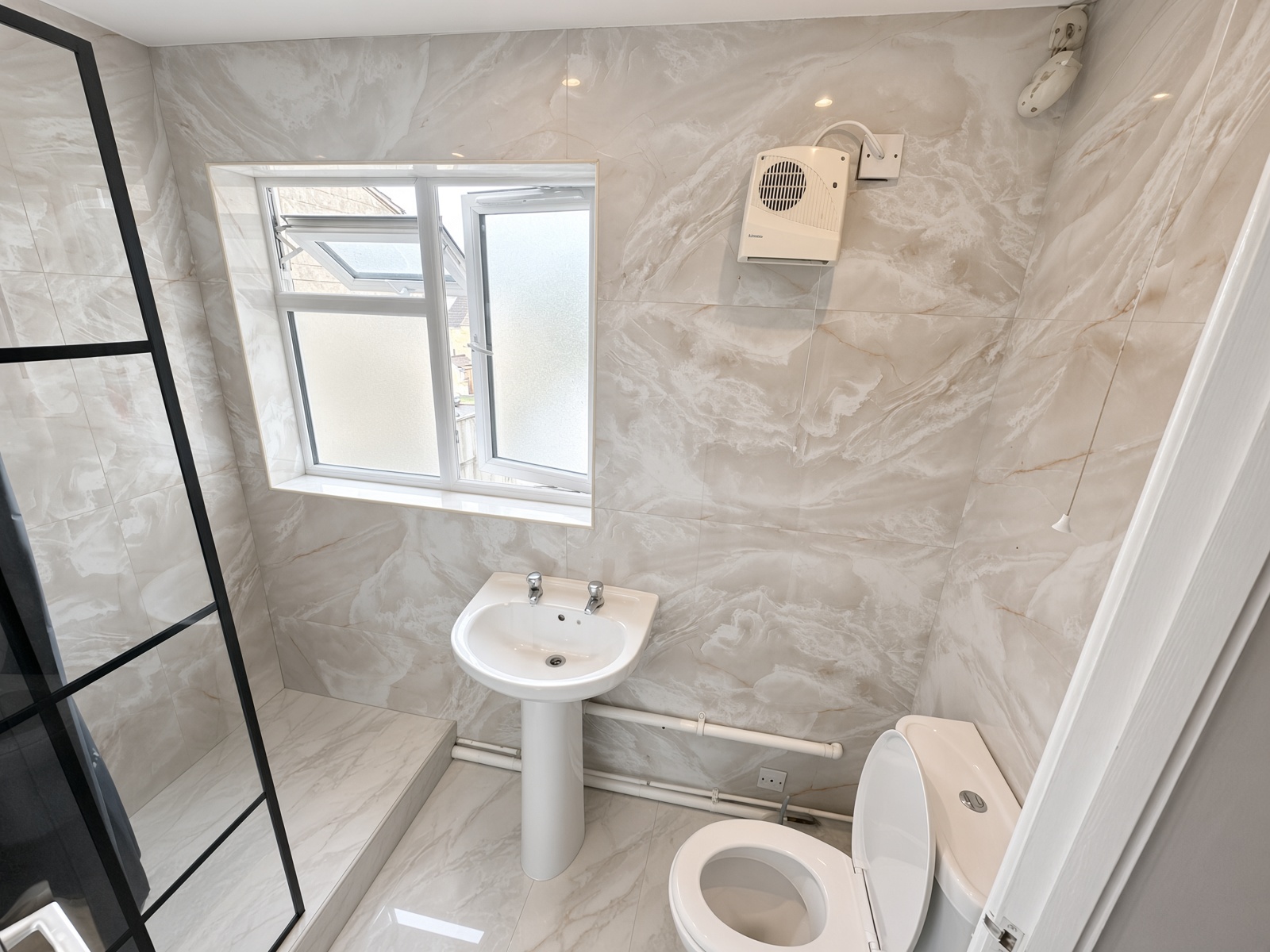 Bathroom with marble-effect tiles, a pedestal sink, and a walk-in shower