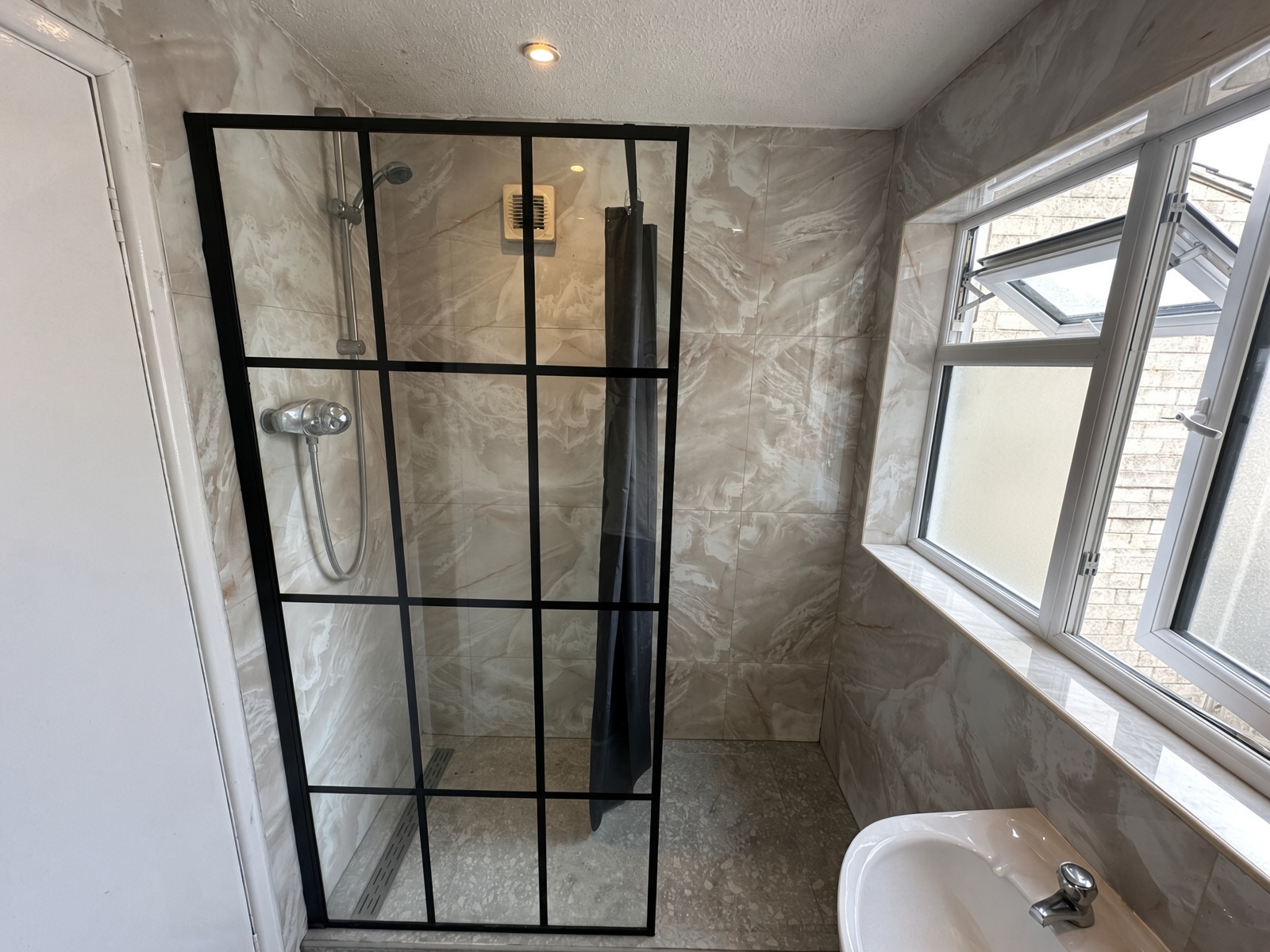 Walk-in shower with a black-framed glass screen