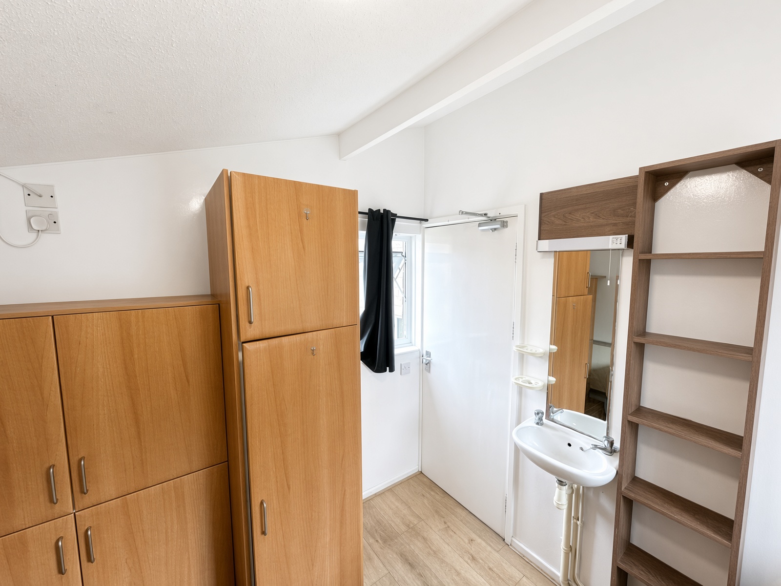 Bedroom with light-wood wardrobes and a wall-mounted washbasin