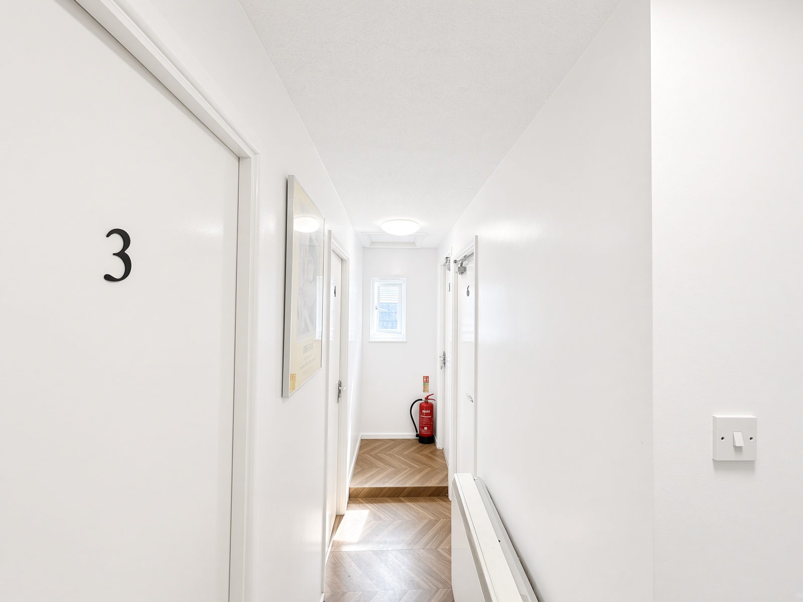Hallway with herringbone flooring and white doors numbered 3 and 6