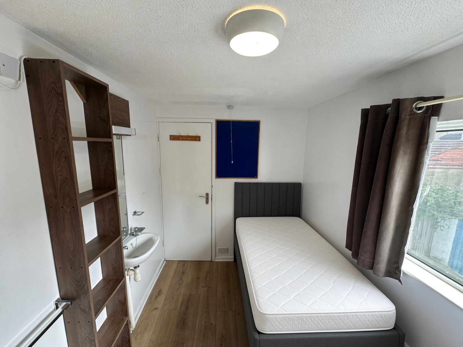 Bedroom with a grey headboard, a washbasin, and brown curtains