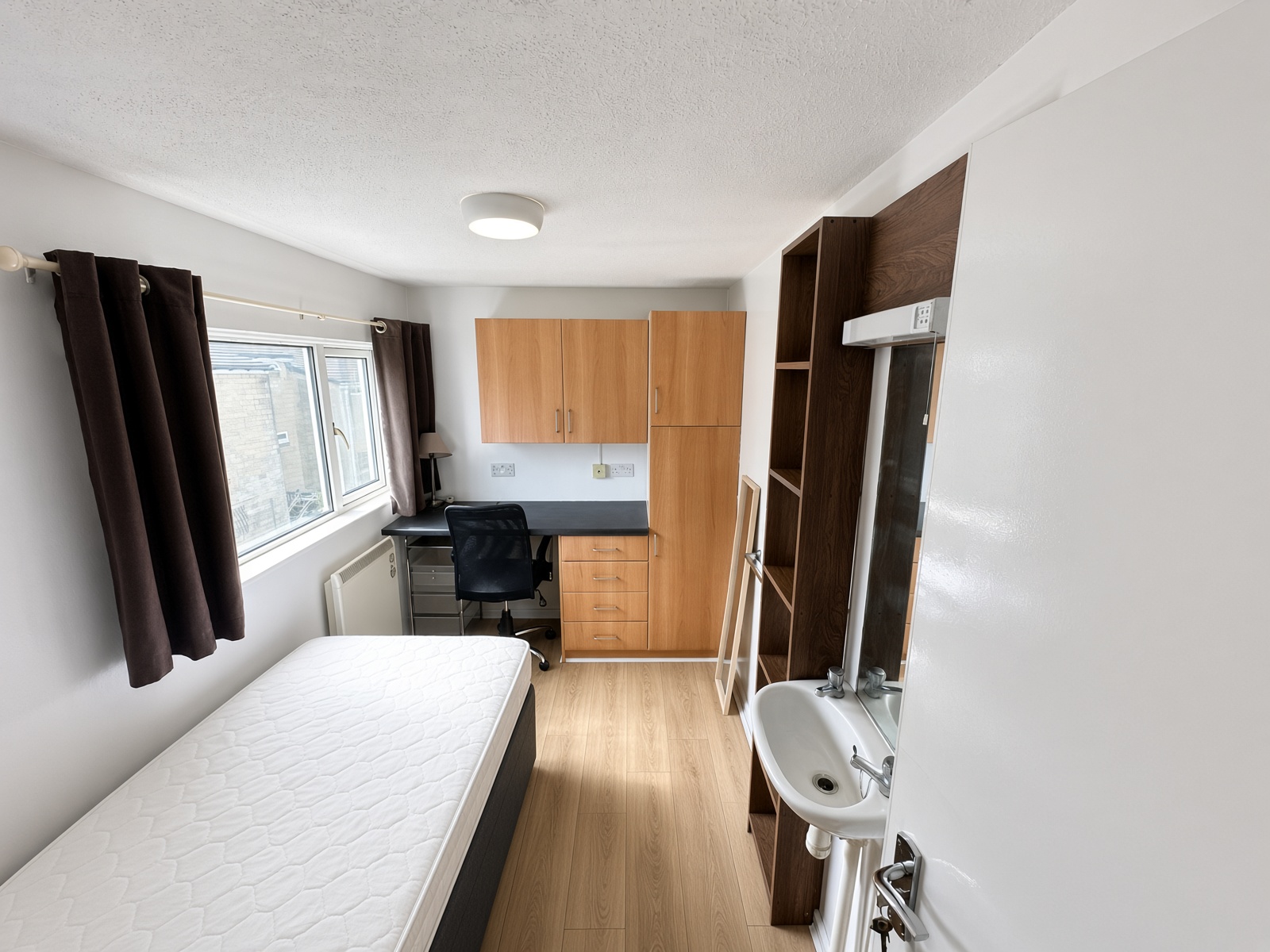 Bedroom with a built-in desk, a washbasin, and a window over the bed