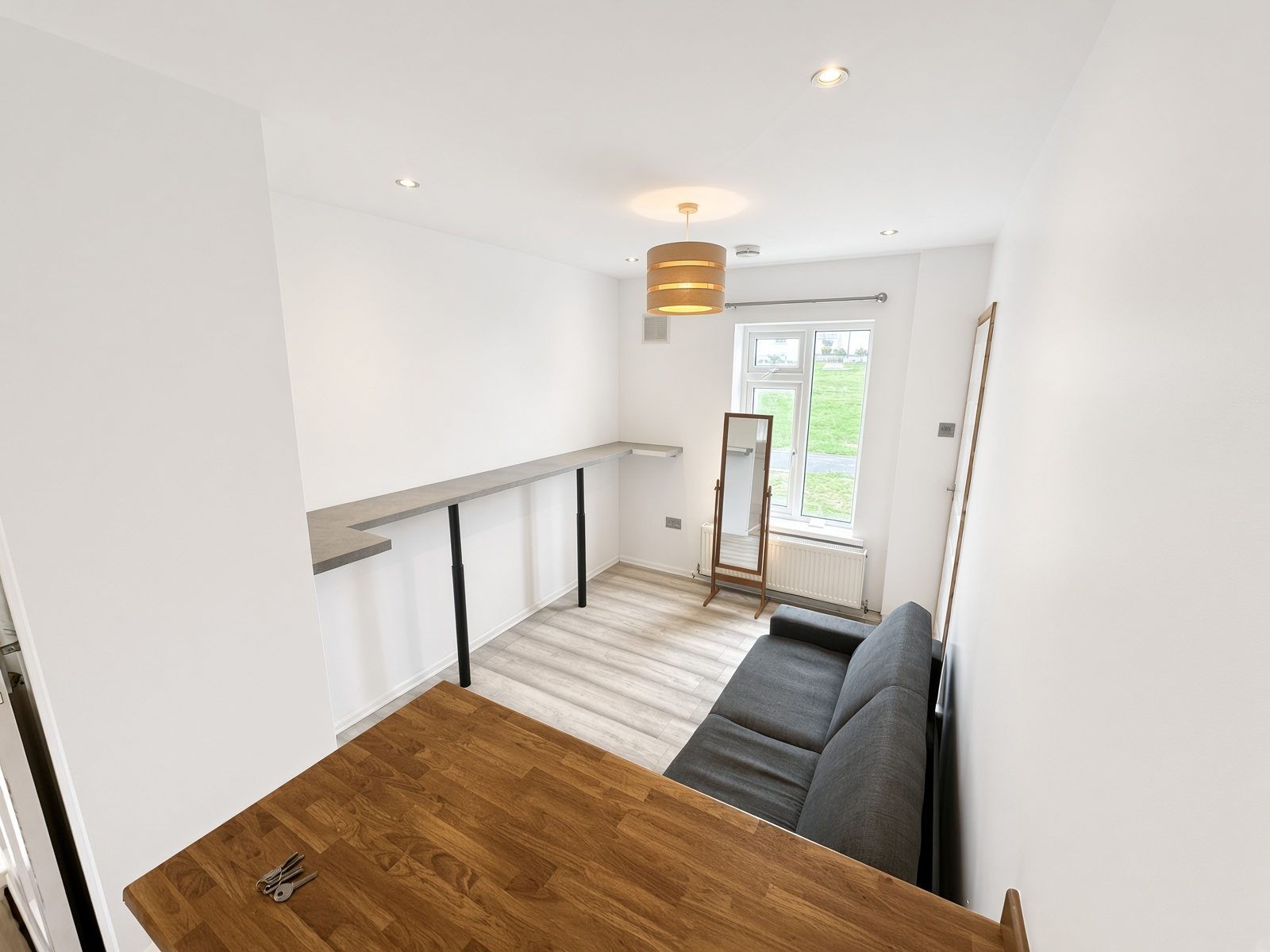 Living room from the kitchen island, with a breakfast bar, sofa, and garden window