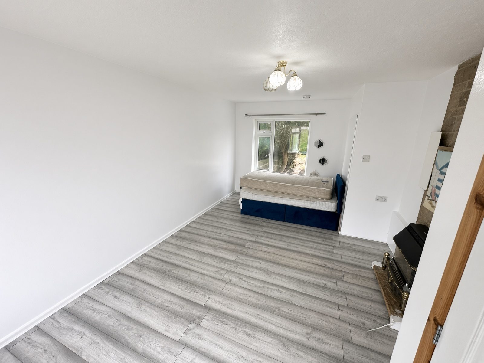 Bedroom with a blue divan, laminate floor, and a fireplace