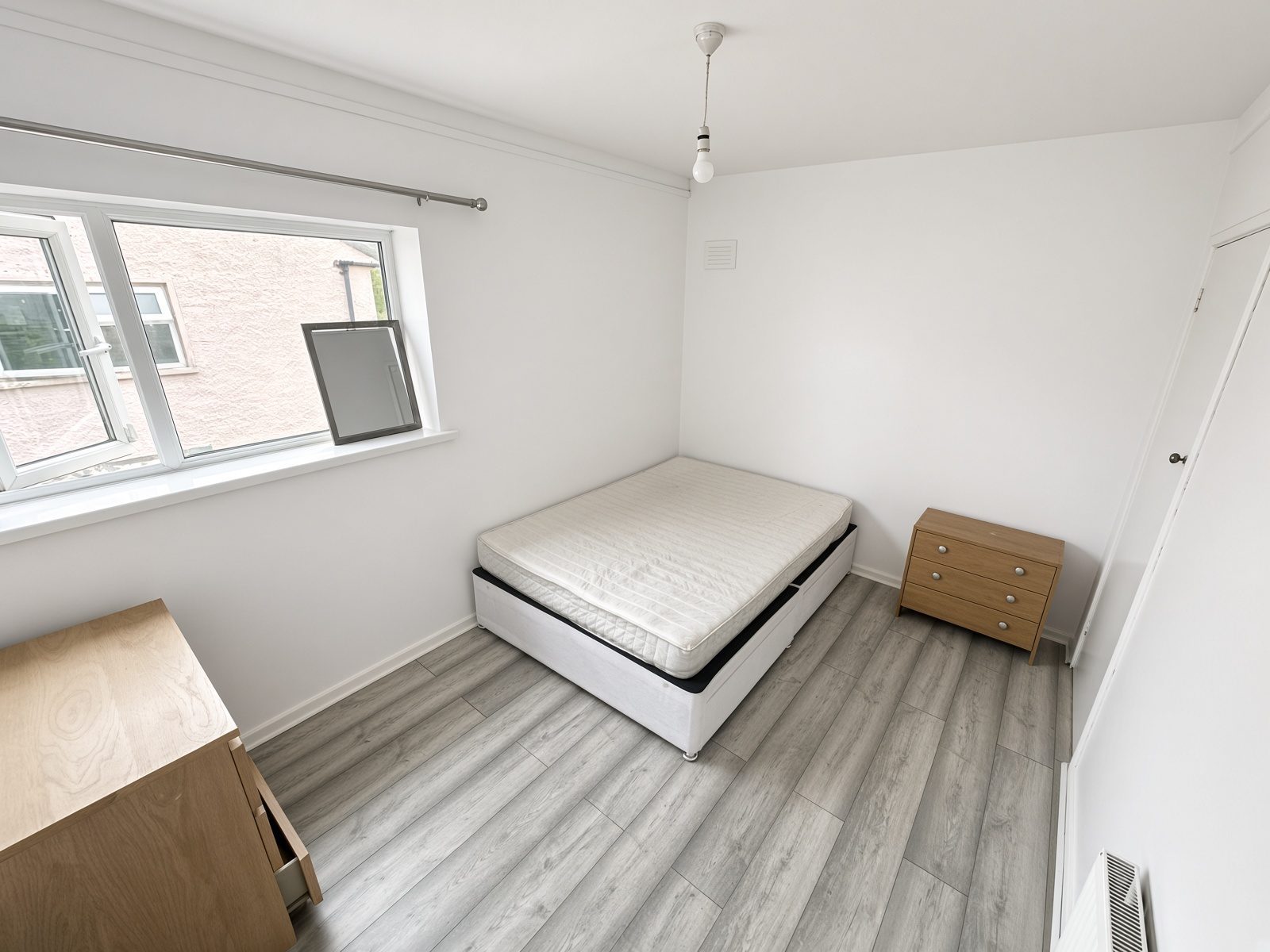 Bedroom with a white ottoman bed, oak chest, and bedside drawers