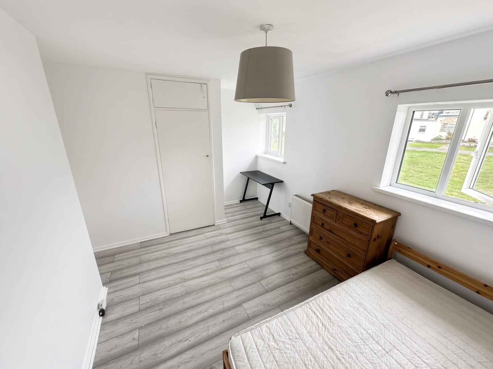Same bedroom from the opposite angle, showing the desk and cupboard door